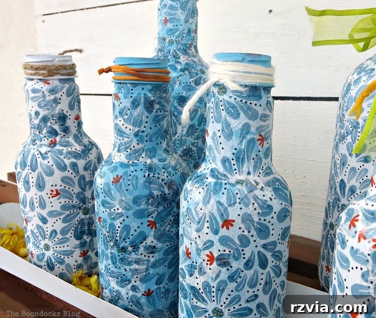 Finished Decoupaged bottles set in a chicken feeder, demonstrating a creative display idea.
