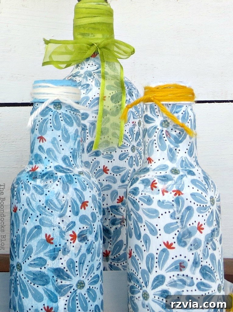 Three decoupaged bottles, a collection of completed upcycled crafts.