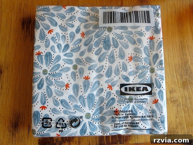 Ikea paper napkins with blue flowers in package on a wooden table surface, providing inspiration for the decoupage project.