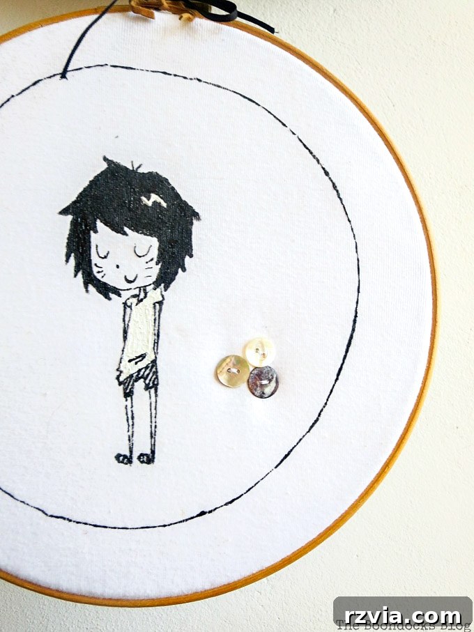 Upcycled T-shirt Wall Decor 11 Close up of hoop wall art made from an upcycled tshirt, featuring a girl character design and three thoughtfully sewn on buttons, ready to adorn a wall.
