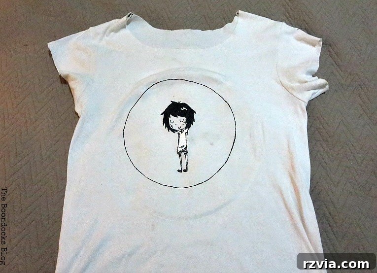 Upcycled T-shirt Wall Decor 3 Old white tshirt with a circle and an image of a girl character in the middle, ready for upcycling.