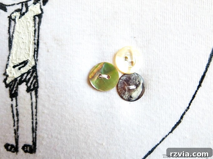 Upcycled T-shirt Wall Decor 9 Close up of three decorative buttons sewn onto the white t-shirt, adding texture and hiding an imperfection.