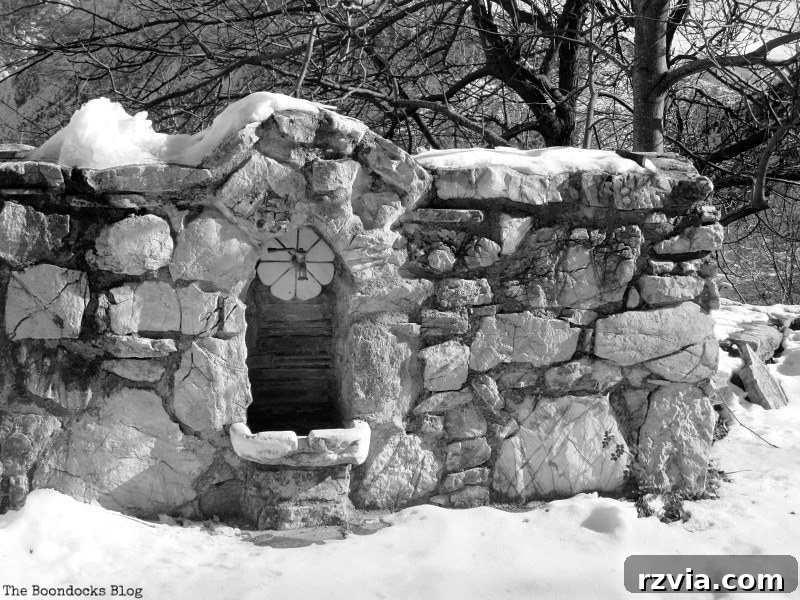 The White Crowns of Greece 11 Rustic stone wall with a water faucet covered in snow, showcasing traditional mountain architecture and the winter environment in Greece.
