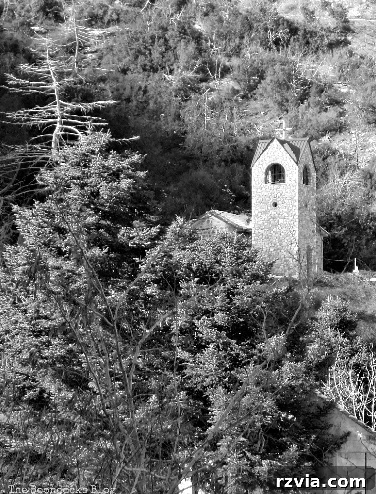 The White Crowns of Greece 20 A charming Greek Orthodox church standing peacefully among snow-dusted trees in a mountain village, symbolizing faith and community.