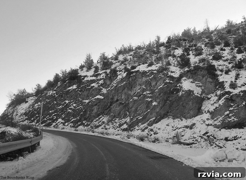 The White Crowns of Greece 5 A black and white view of the winding road ascending the snowy Greek mountain, highlighting the journey's challenge and the desolate beauty of the winter landscape.