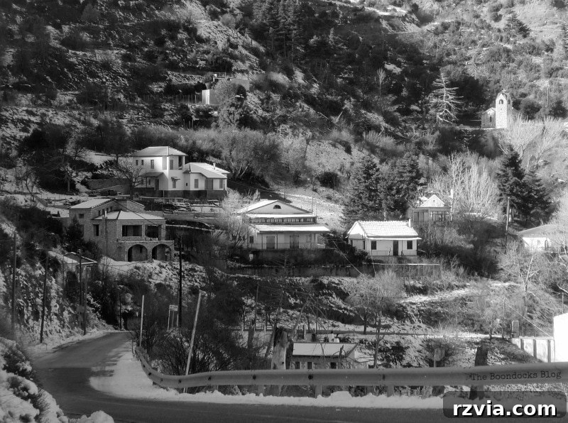 The White Crowns of Greece 7 Black and white image of the final destination village high in the snowy Greek mountains, showing traditional architecture amidst winter scenery.