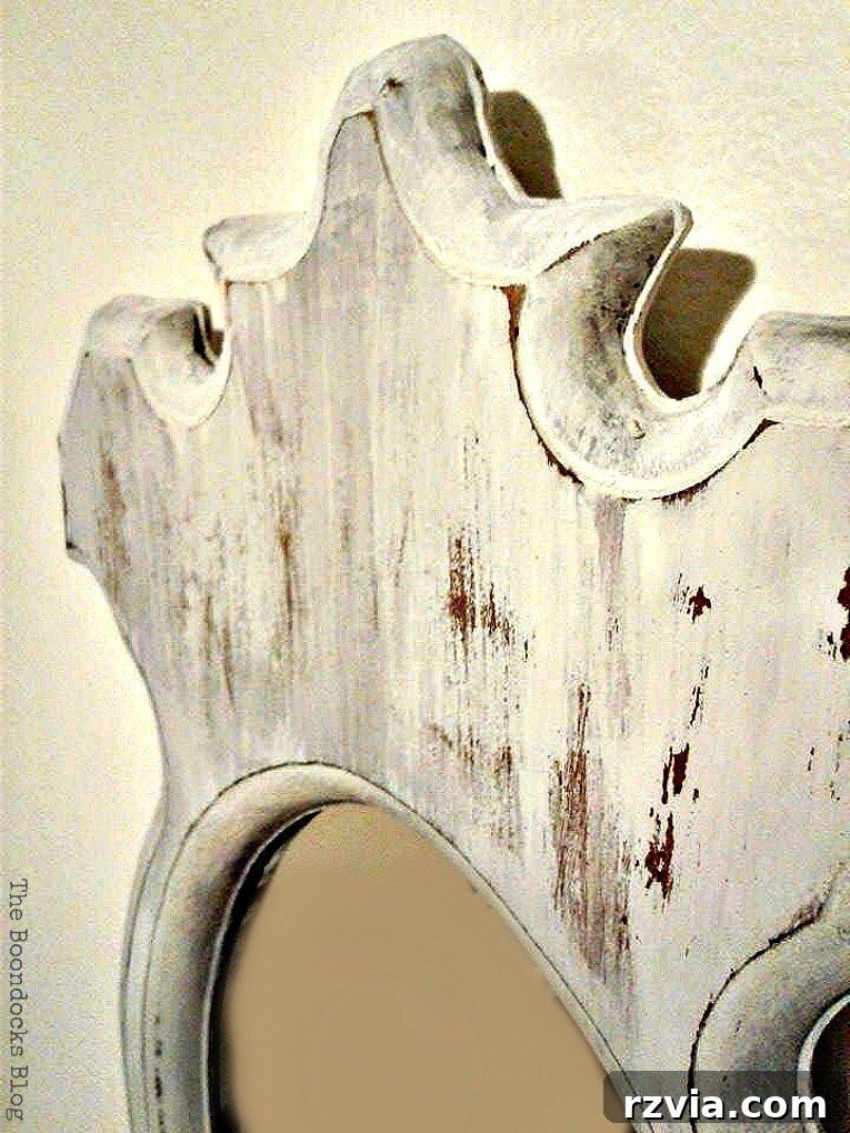Close-up details of intentional distressing on the painted mirror frame, revealing hints of original wood. theboondocksblog.com