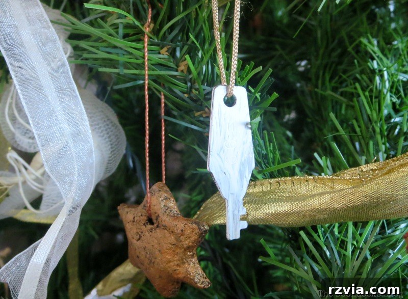 A close-up of thick gold ribbon on the tree, accompanied by a white-painted key ornament.