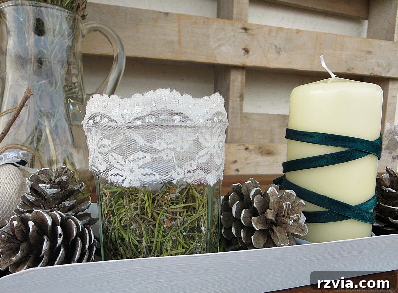 Detailed shot of the Christmas centerpiece showing lace accents on the rosemary jars and a green ribbon on the candle, emphasizing the elegant, natural DIY decor. Photo by www.theboondocksblog.com