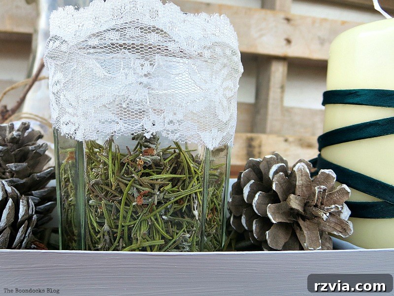 Close-up detail of a jar with rosemary and its delicate flowers, part of an easy green Christmas centerpiece, highlighting the natural beauty. Photo by www.theboondocksblog.com