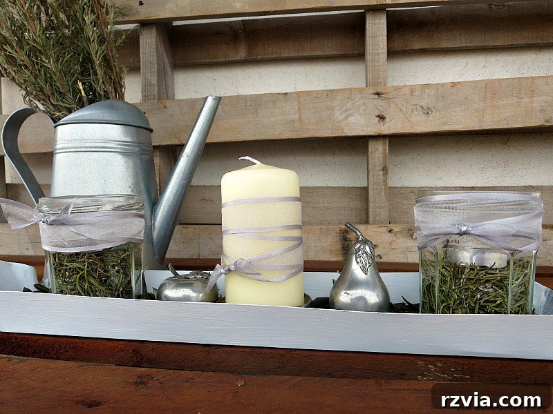 A second version of the Christmas centerpiece featuring a white chicken feeder, olive leaves, rosemary, grey ribbons, and elegant metal apple and pear accents. Showcases a more refined style. Photo by www.theboondocksblog.com