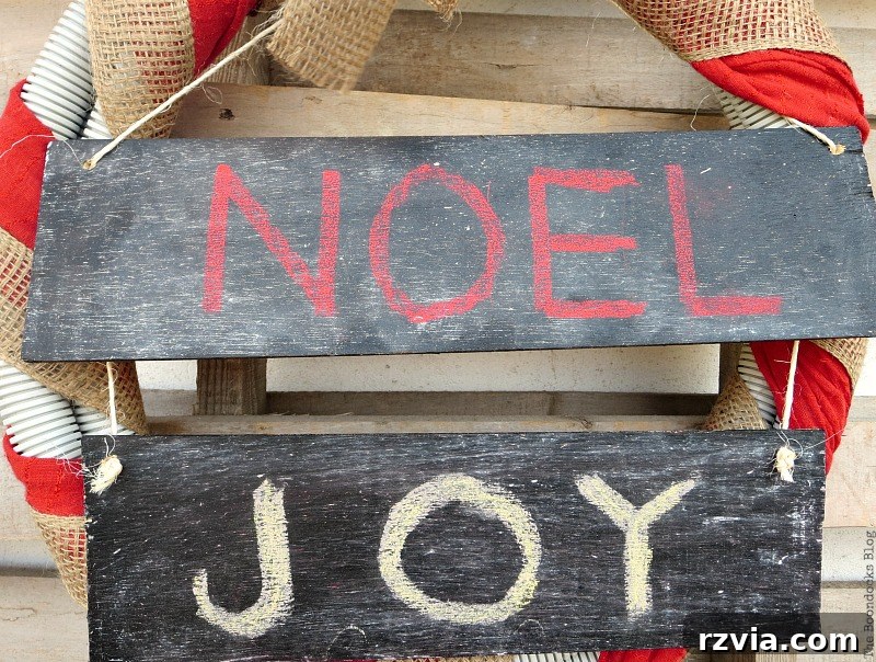 One of the chalkboard signs cut into two pieces, positioned to be added to the Christmas wreath.