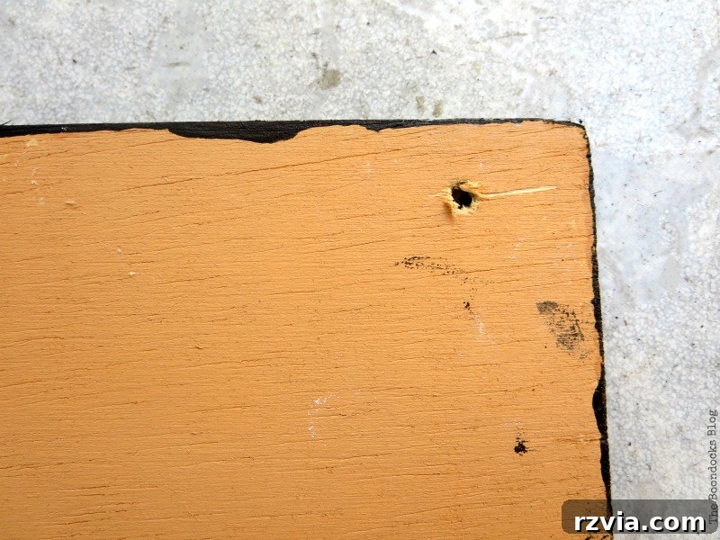 Close-up of a wood chalkboard sign with a hole carefully made in the corner for hanging. The paint is dry and ready for the next step.