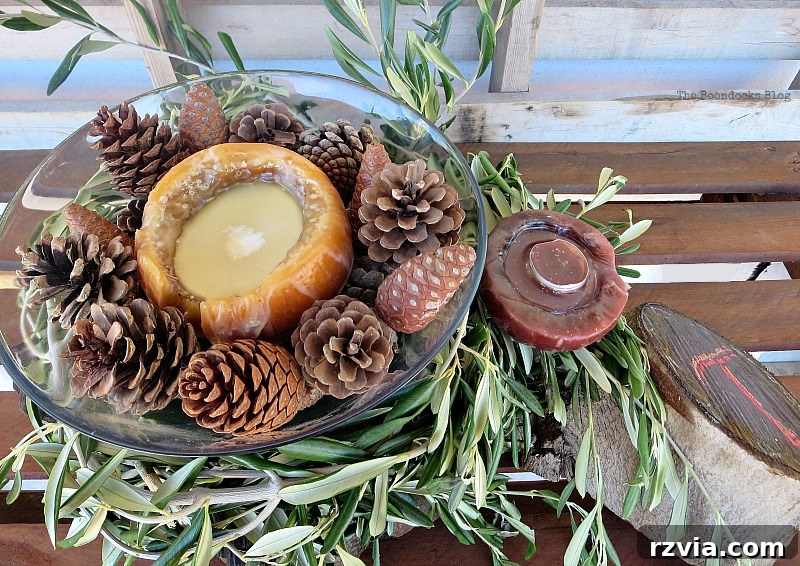 Autumn's Bounty for Your Table 14 A combined centerpiece arrangement showcasing a glass bowl with a candle and pinecones, placed over olive branches, alongside a rustic wood stump with another candle, creating a harmonious display.
