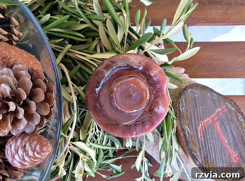 Autumn's Bounty for Your Table 15 Close-up of a central candle nestled among pinecones on a rustic wood stump, with a hand-chalked 'T' for Thanksgiving visible on the wood's end.