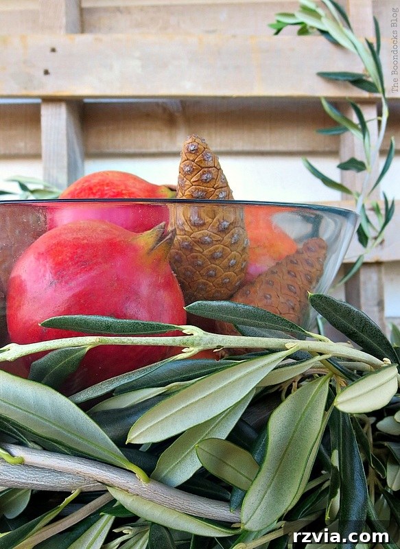 Autumn's Bounty for Your Table 18 A complete natural Thanksgiving centerpiece featuring vibrant pomegranates, rustic pinecones, and elegant olive branches, arranged on a natural wood base.