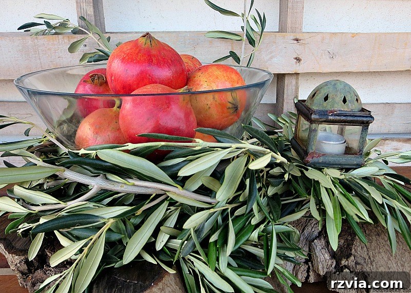 Autumn's Bounty for Your Table 8 A beautiful Thanksgiving centerpiece featuring a glass bowl filled with pomegranates, nestled within an olive branch circle, with a rustic lantern placed to the side.