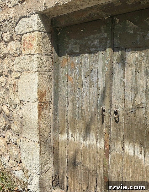 Stone Chronicles of the Shore 16 An aged wooden door with intricate carvings and weathering, found in the historic old stone buildings of the waterfront. Image by www.theboondocksblog.com