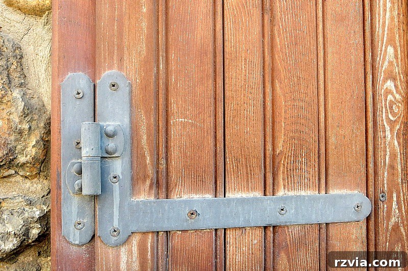 Stone Chronicles of the Shore 5 Detailed shot of a weathered wooden window shutter on a historic stone building, showing authentic rustic details. Image by www.theboondocksblog.com