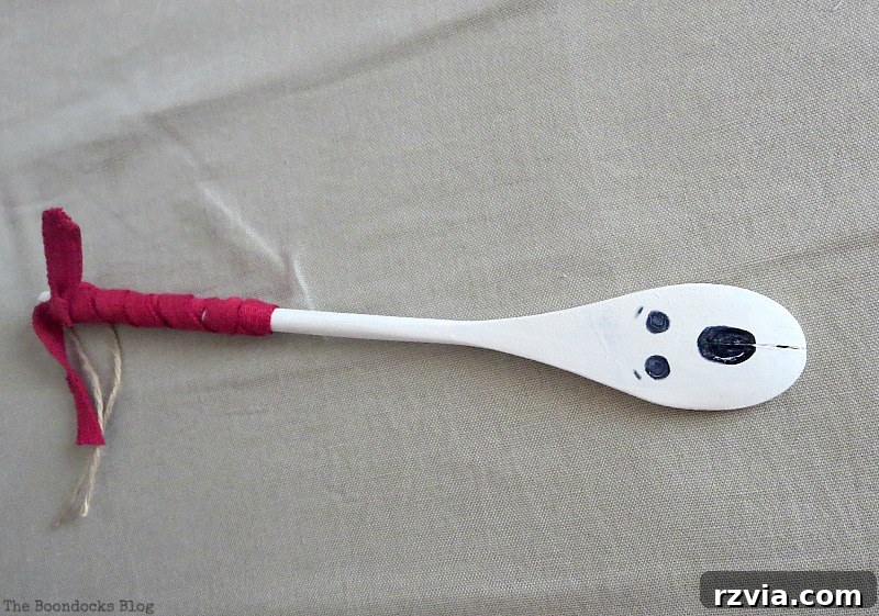 Transform Tubes into a Halloween Wreath 7 A wooden spoon painted white with a hand-drawn ghost face, ready to be added to the wreath.