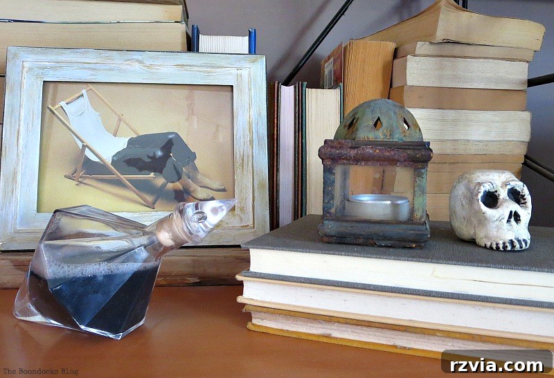 A vignette with an odd shaped bottle, skeleton head, and mysterious art, perfect for Halloween decor.