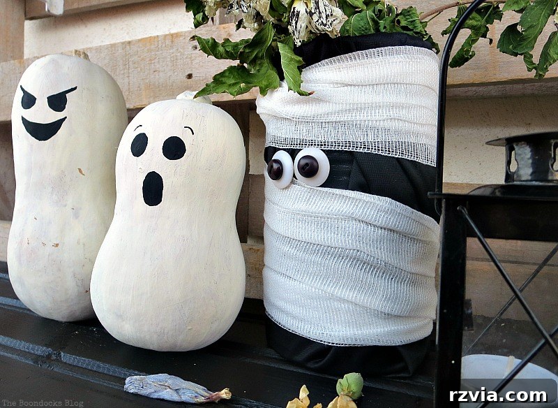 A tea light holder next to mummy and gourds, enhancing Halloween vignette ambiance