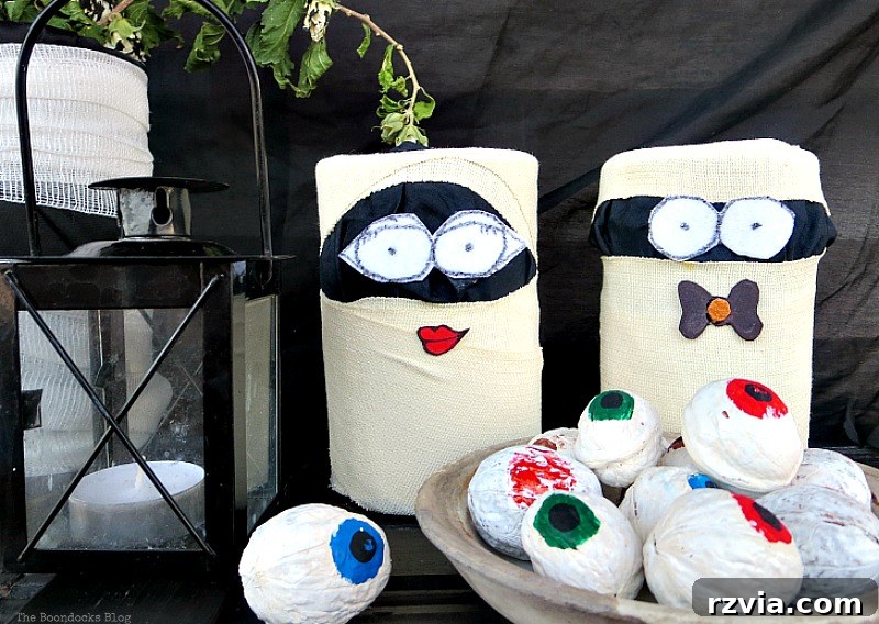 Tin mummies wrapped in black fabric and gauze, with felt eyes for a Halloween vignette