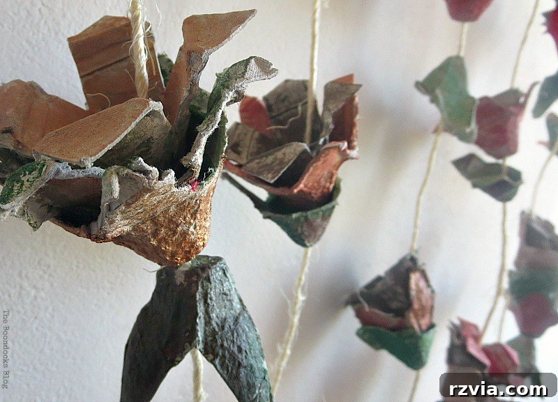 A cluster of painted egg carton flowers in warm fall colors, highlighting the rich autumnal palette used in this upcycled craft.