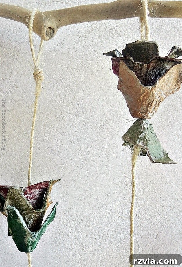Artistic display of egg carton flowers hanging from a piece of driftwood, showcasing a rustic and natural aesthetic.