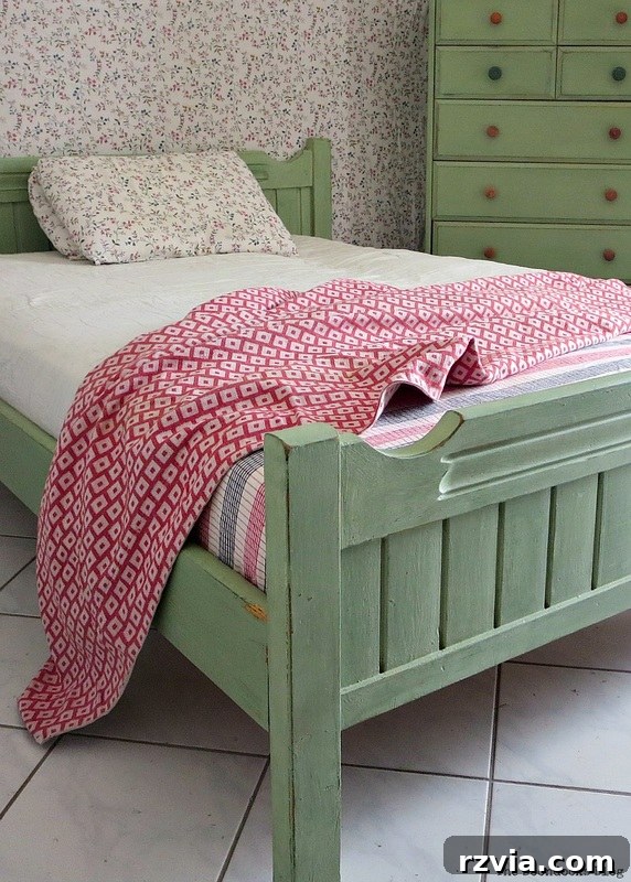 The beautifully painted and distressed footboard of the bed, contributing to the overall vintage charm of the bedroom set.