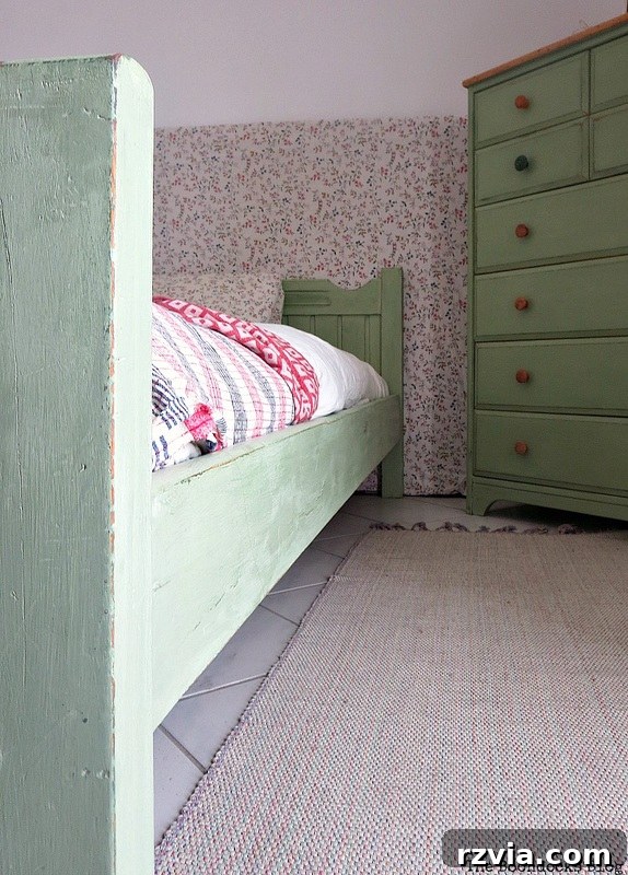 Close-up detail of the footboard's distressed finish, showing the subtle wear and layered green hues.