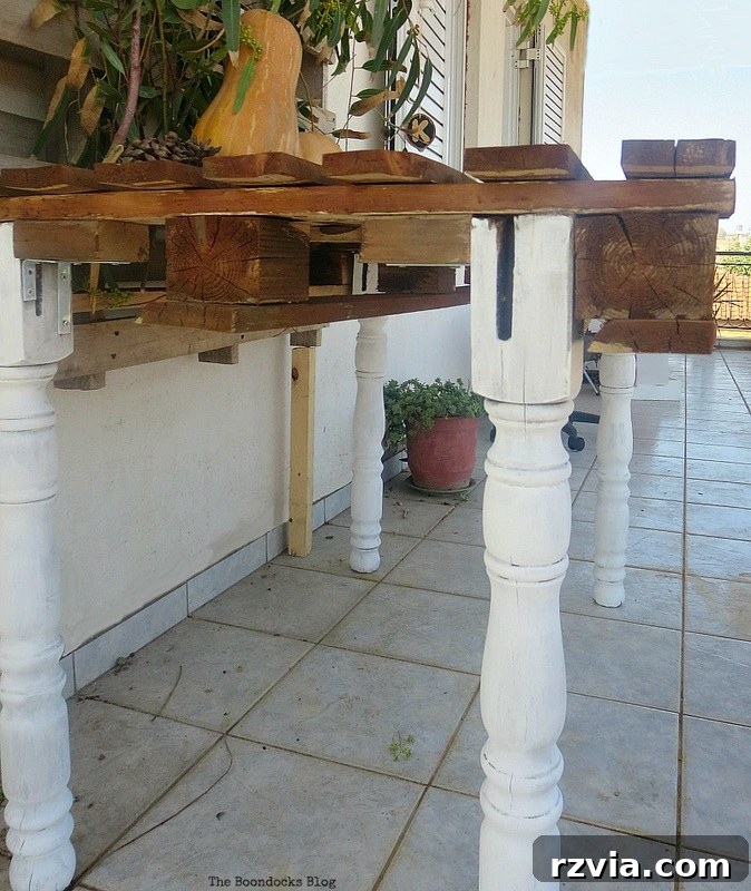 Upcycled Elegance: Crafting a Pallet and Salvaged Wood Table 14 The completed DIY pallet table set up on a balcony, functioning as an outdoor photography station, with another pallet as a rustic backdrop. www.theboondocksblog.com