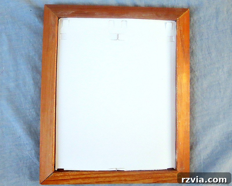 DIY Earring Storage Made Simple 4 A piece of cardboard being carefully cut with scissors to fit inside a wood picture frame.