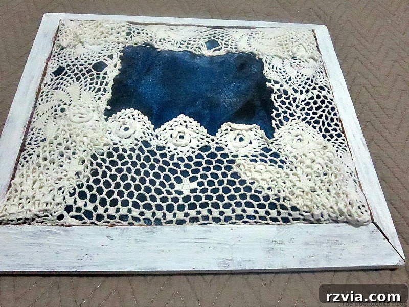 DIY Earring Storage Made Simple 9 The completed fabric and doily-covered cardboard being carefully placed and fitted into the painted wood frame.
