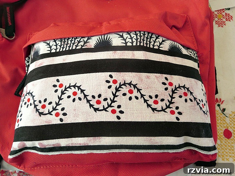From Fabric Scraps to Adventure Packs 11 Gluing fabric onto the bottom pocket of the backpack, covering the undesirable sticker.