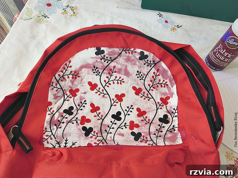 From Fabric Scraps to Adventure Packs 10 Applying fabric glue to attach the cut fabric pieces to the backpack surface.