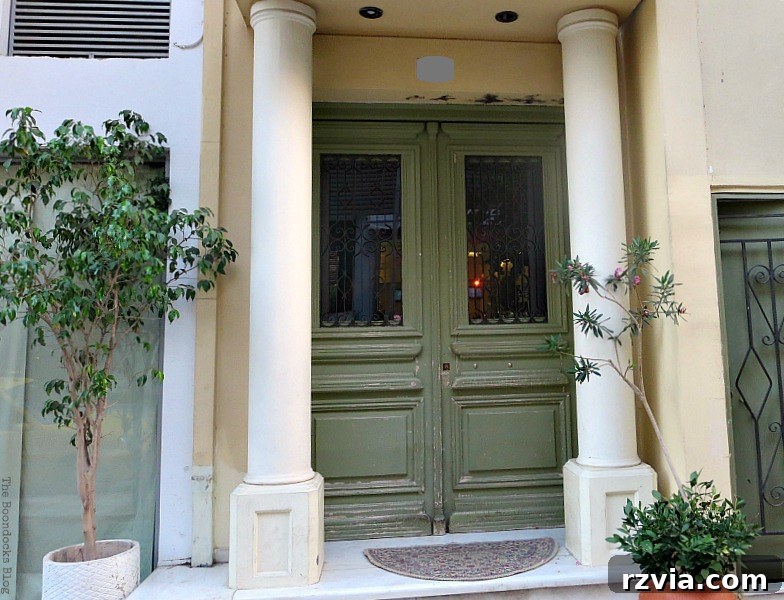 Elegant green door flanked by classic columns, a common sight in traditional Greek architecture, featured on www.theboondocksblog.com.