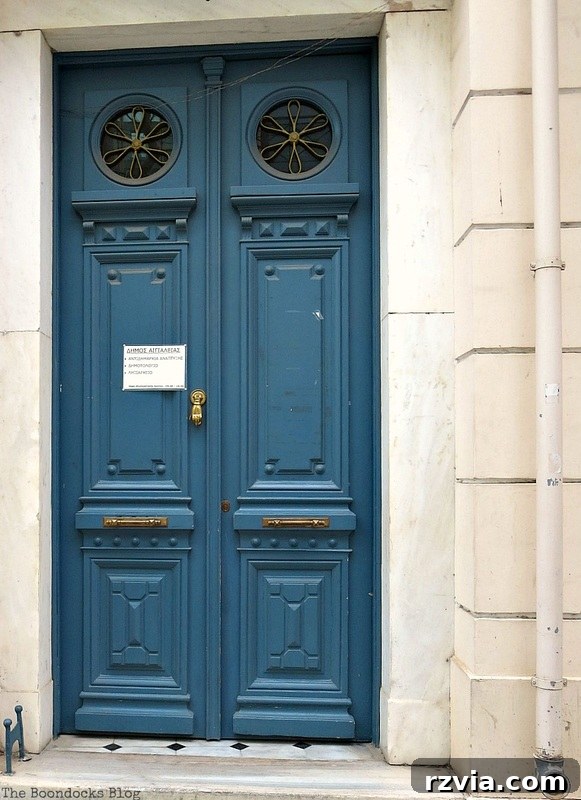 Distinctive blue door with unique circular windows, adding character to a Greek building, as seen on www.theboondocksblog.com.