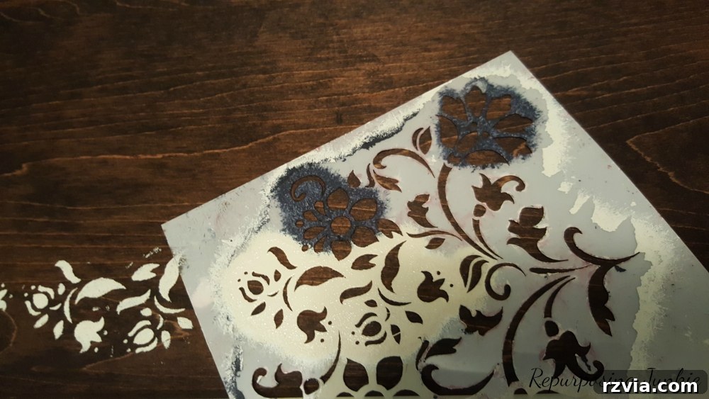 From Curb to Chic: Coffee Table's Gorgeous New Look 8 Applying a stencil to the coffee table top, showcasing the artistic detail in this furniture makeover.