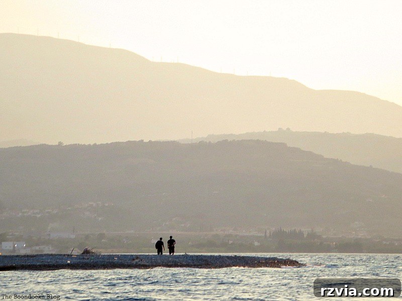 Two strollers enjoying the beach as the sun sets, creating long shadows