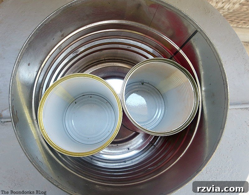 Smaller tin cans placed inside a larger can to create compartments, a smart solution for holding branches upright in a DIY vase.