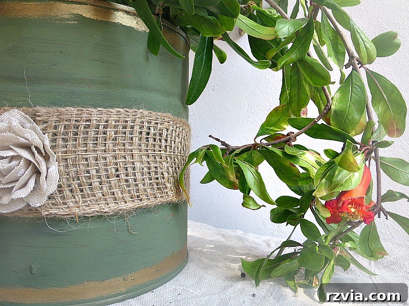 Pomegranate branches being carefully placed into the newly repurposed tin can vase, creating a natural and elegant display.
