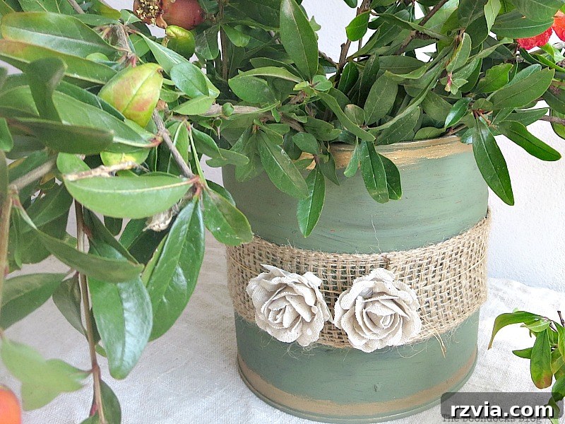 The completed repurposed tin can vase, filled with pomegranate branches, showcasing the beautiful DIY home decor item.