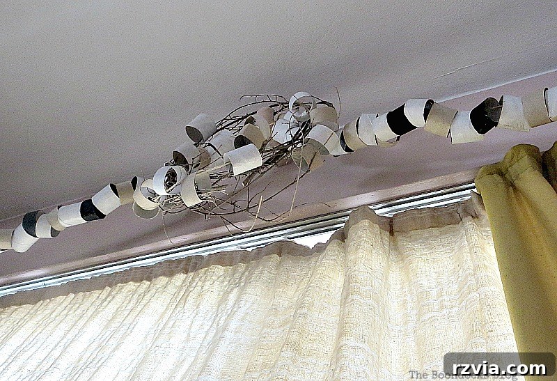 An upward, under-view perspective of the paper roll garland and wreath installation, showcasing its textural depth and the ingenious way it effectively conceals the underlying curtain brackets, enhancing the room's aesthetic.
