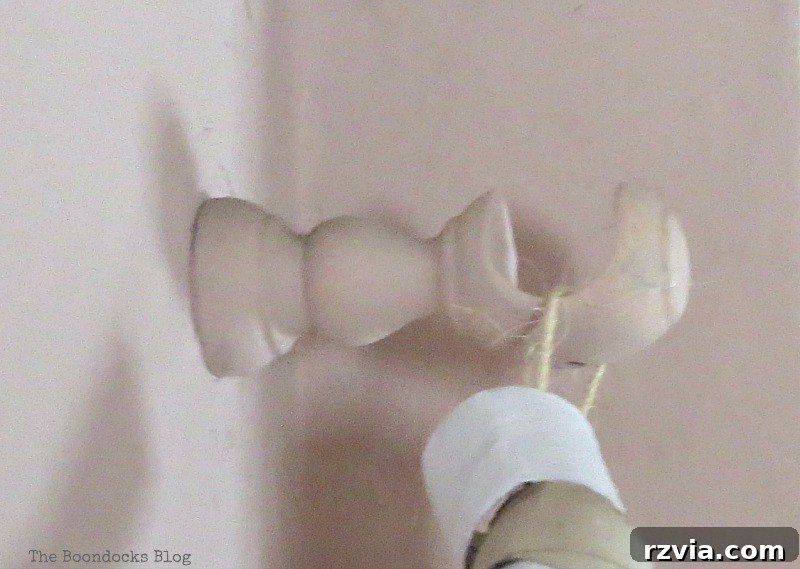The curtain rod bracket after being painted in an attempt to match the wall color, clearly illustrating an unsuccessful blending effort and underscoring the need for a more creative decorative solution. This image captures the 'epic fail' moment.