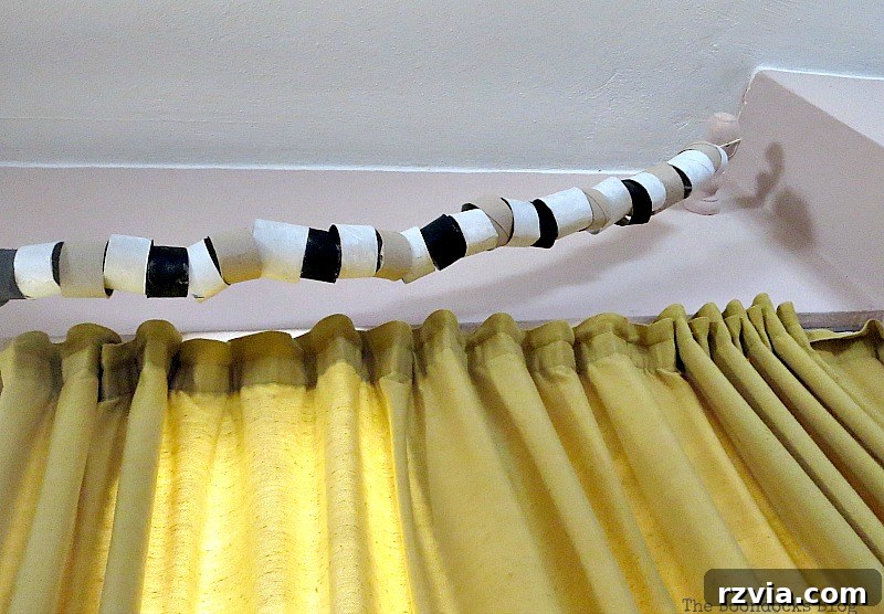 The repurposed paper roll garland, now gracefully repositioned and hanging from the previously unsightly curtain brackets above the sliding door, marking the initial phase of its decorative transformation. This image illustrates the beginning of the creative solution.