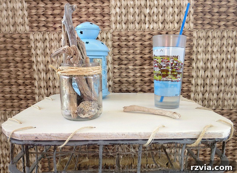 Beyond the Box: Milk Crate Table Reinvention 11 Detailed close up of the freshly painted white table top, featuring a refreshing drink, a decorative blue lantern, and a jar with natural driftwood, showcasing the smooth, renewed surface.