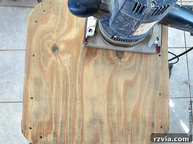 Beyond the Box: Milk Crate Table Reinvention 6 Sanding the plywood top of the table with an electric sander to prepare it for painting, highlighting the removal of old finish.