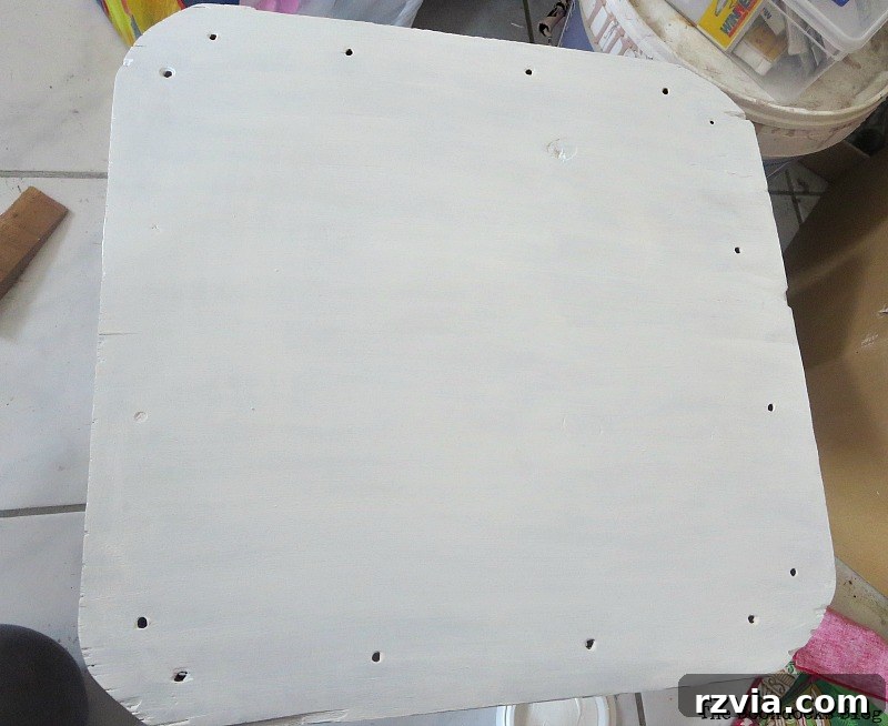 Beyond the Box: Milk Crate Table Reinvention 7 Applying white colored varnish to the plywood table top with a brush, demonstrating the painting process.