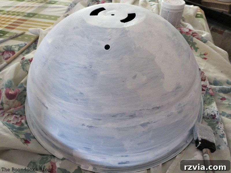Painting the old barbecue grill with chalk paint, a key step in creating a repurposed Earth Day planter